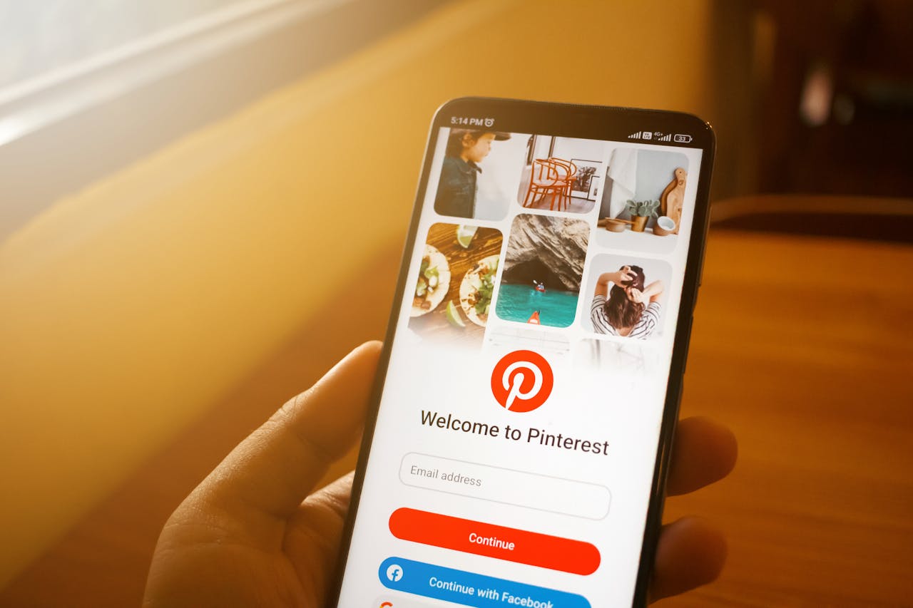 Close-up of smartphone displaying Pinterest login screen in a cozy indoor setting.